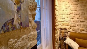 A room with a stone wall, a window with curtains, a sofa, and a painting of a deer. - Paris Loft for 4 by Châtelet & Montorgueil & Metro (PARIS)