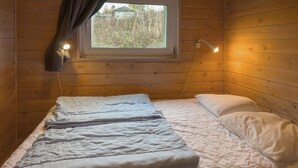 A wooden room with a bed, a window, and a wall-mounted lamp. - Stunning home in Knebel (Knebel)
