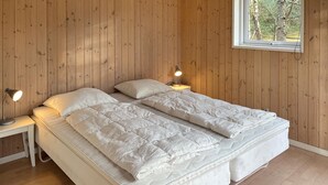 A bedroom with two beds, wooden walls, a window with a view of trees, and bedside lamps. - Beautiful home in Hadsund with WiFi (Hadsund)