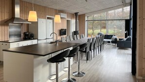 A modern kitchen with a central island, bar stools, and a dining area with a sofa and chairs. - Beautiful home in Hadsund with WiFi (Hadsund)