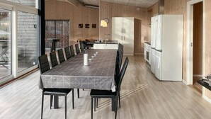 A modern kitchen with a dining area, wooden walls, and a large window. - Beautiful home in Hadsund with WiFi (Hadsund)