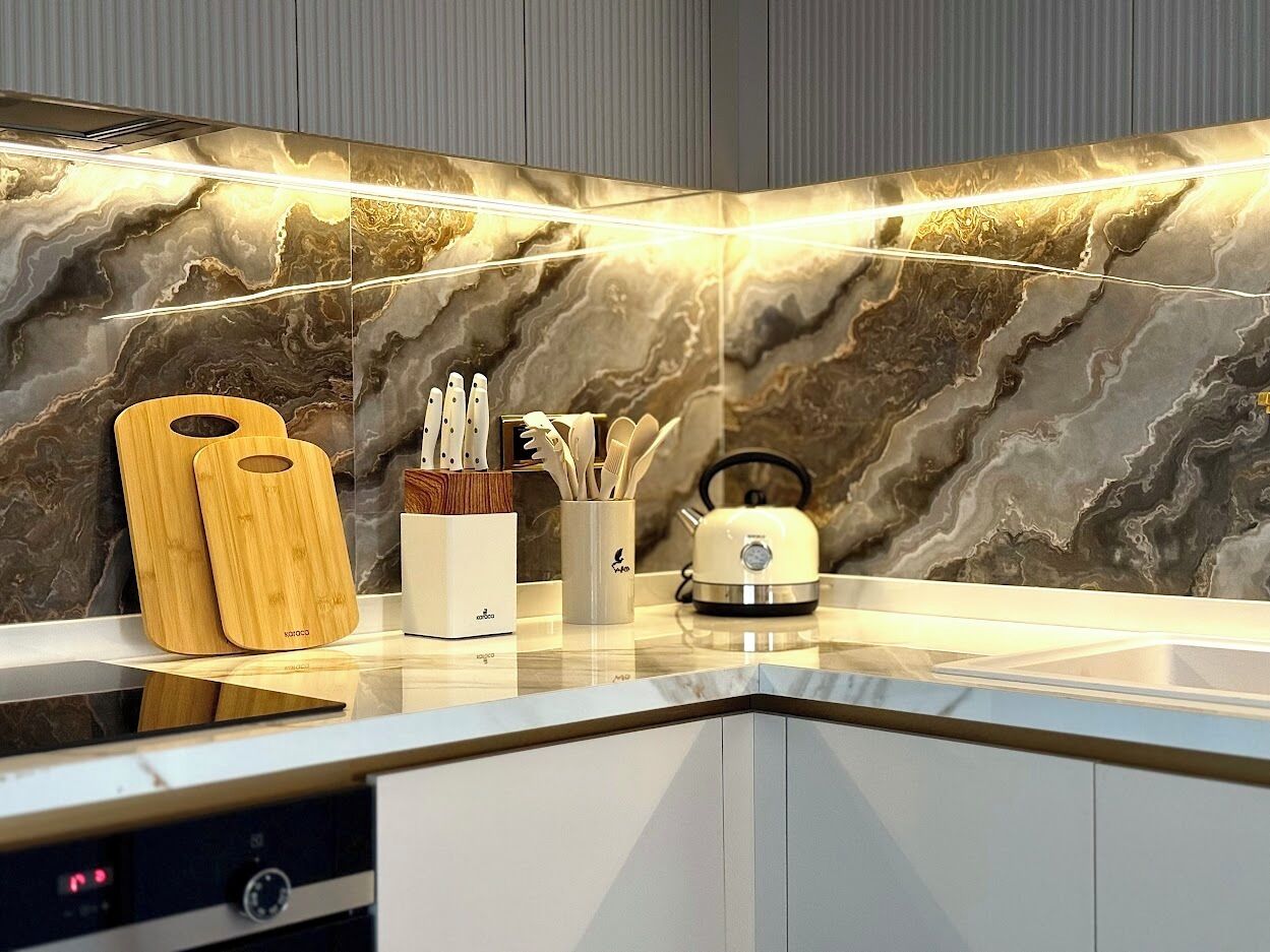 Una cocina moderna con salpicadero de mármol, estufa integrada y tablas de cortar de madera.