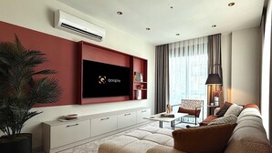 A modern living room with a flat-screen TV mounted on the wall, a sofa set, a coffee table, and a potted plant. - Apartment 2+1 Qoople Excellence B55 designer duplex by the sea (Alanya)