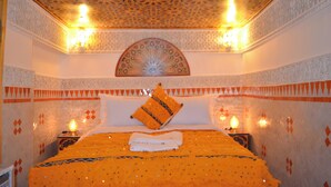 A room with a bed, decorative pillows, and wall sconces. - Riad Dar Salma  (Fes)