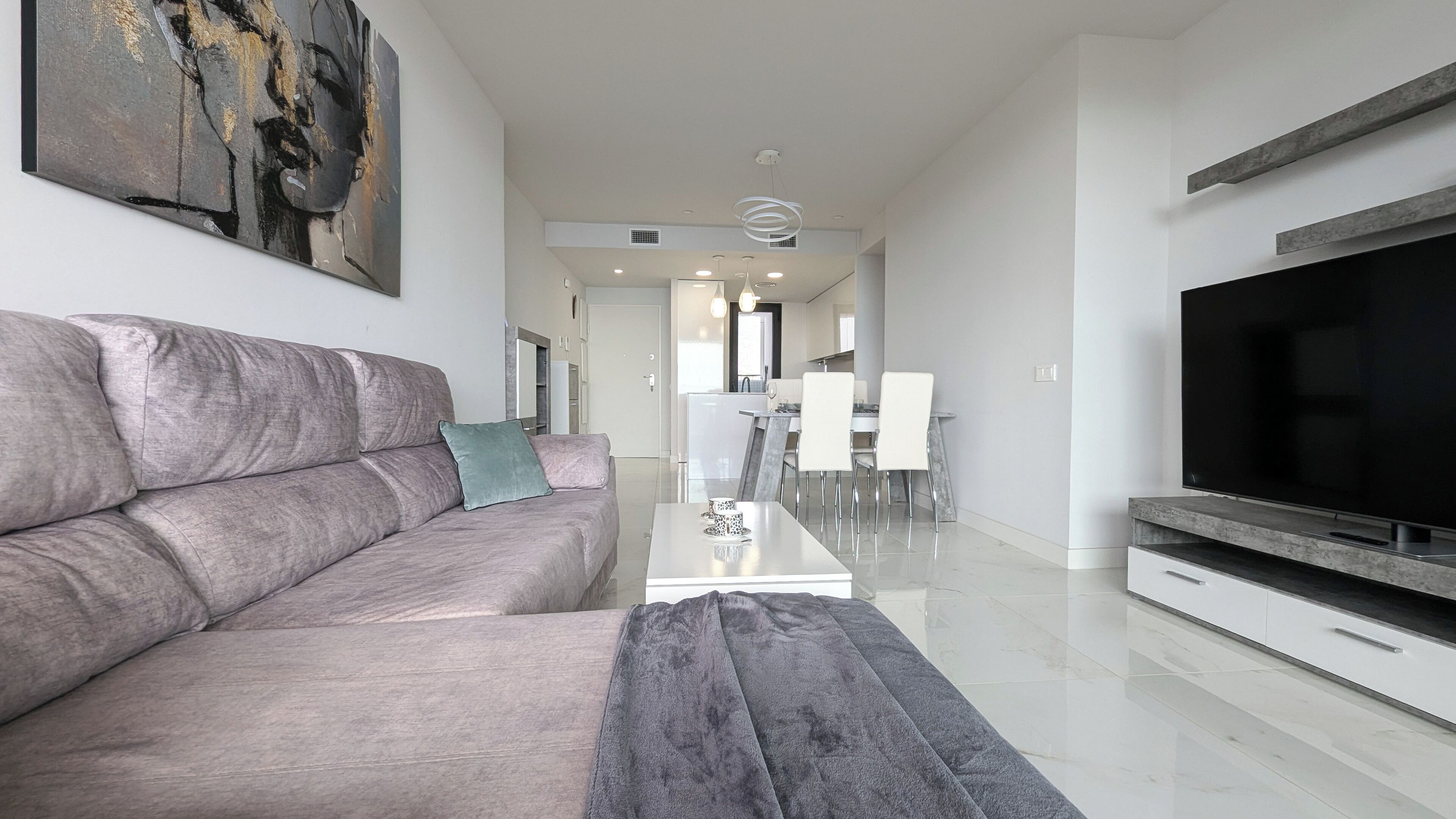 Una sala de estar moderna con un sofá gris, una mesa de centro y un televisor de pantalla plana.
