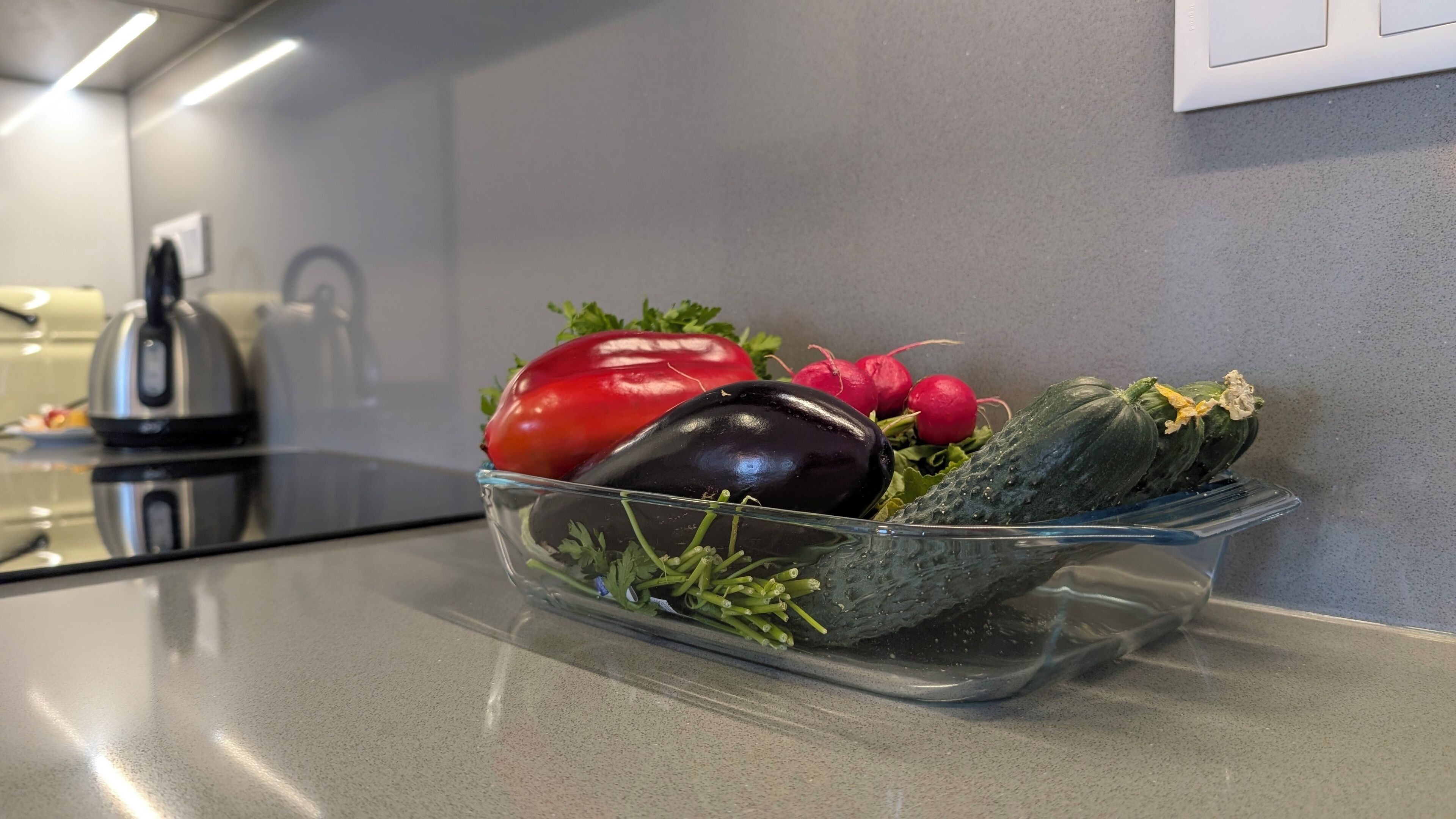 A kitchen counter with a glass dish containing vegetables.