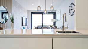 A modern kitchen with a large island, pendant lights, a sink, and a dining area with a view. - Benidorm Beach Apartments (Benidorm)