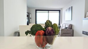 A bowl of vegetables on a kitchen counter with a modern kitchen and living area in the background. - Benidorm Beach Apartments (Benidorm)