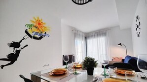 Uma área de refeições com mesa de vidro, cadeiras e um adesivo na parede.