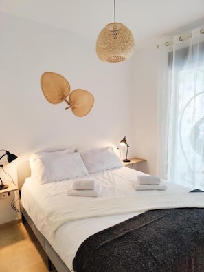Ein Schlafzimmer mit einem Bett, Nachttischlampen und einem Fenster mit Vorhängen.
