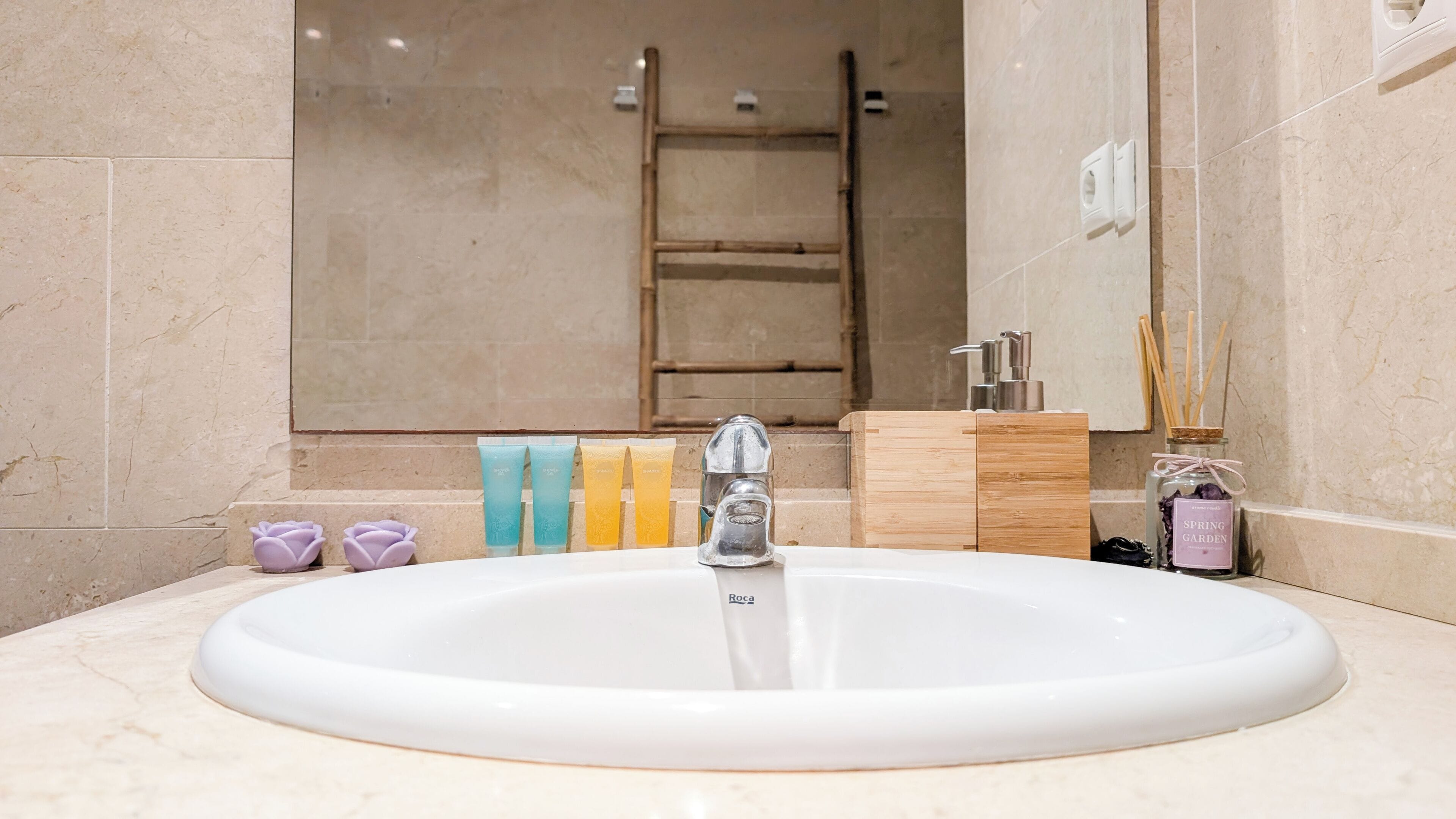 A bathroom with a white sink, a mirror, a wooden cabinet, and toiletries.