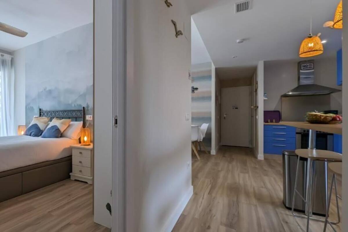Une chambre à coucher moderne avec un lit, une table de chevet et une vue sur la cuisine.