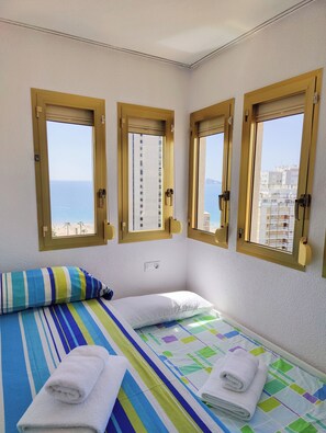 A room with a bed, two windows, and a view of the sea. - Gerona Apartments (Benidorm)