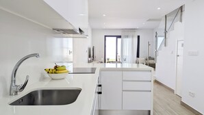 A modern kitchen with a stainless steel sink, a bowl of fruit, and a clean, minimalist design. - Panoramic Apartments (Finestrat)