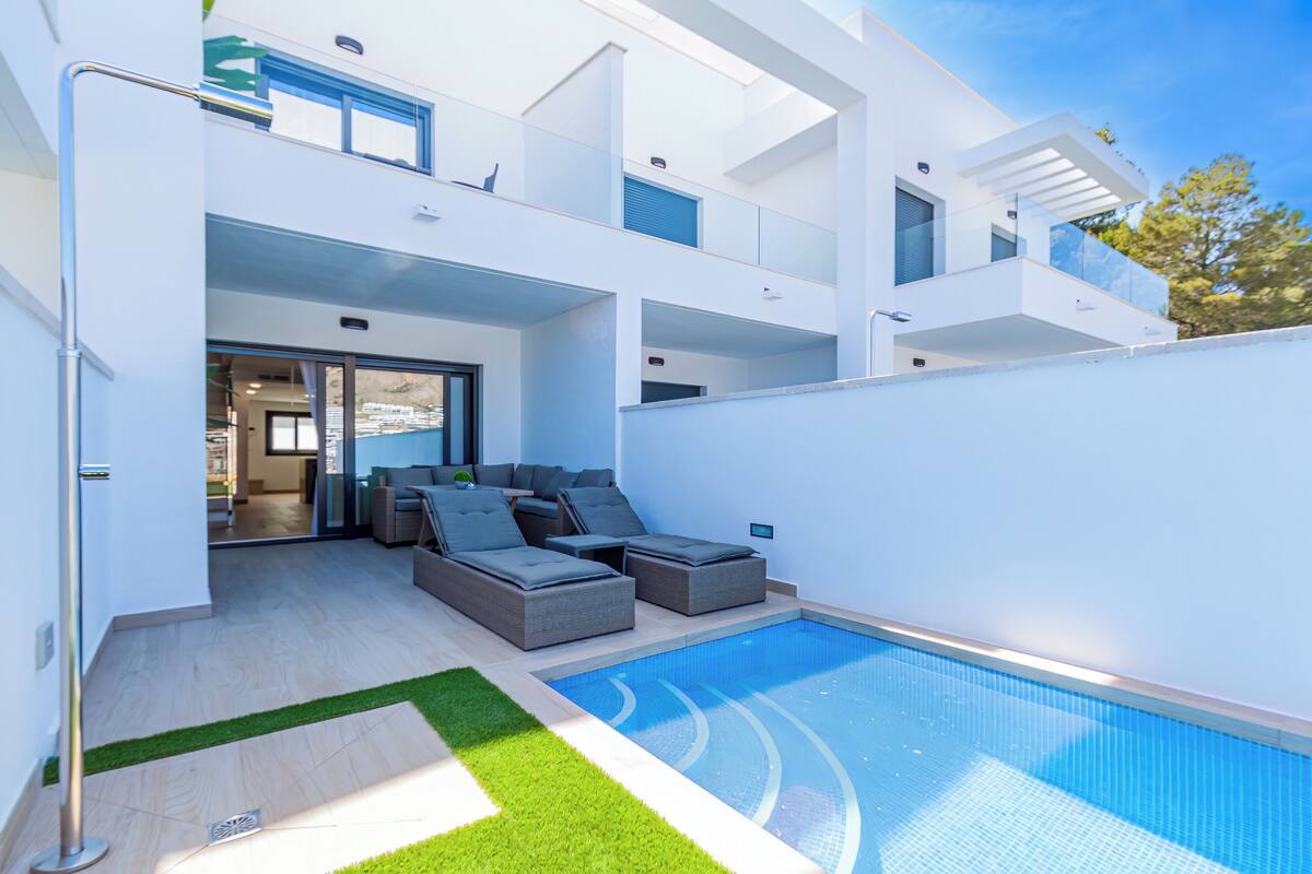A modern two-story house with a swimming pool, outdoor seating, and a view of the surrounding area.