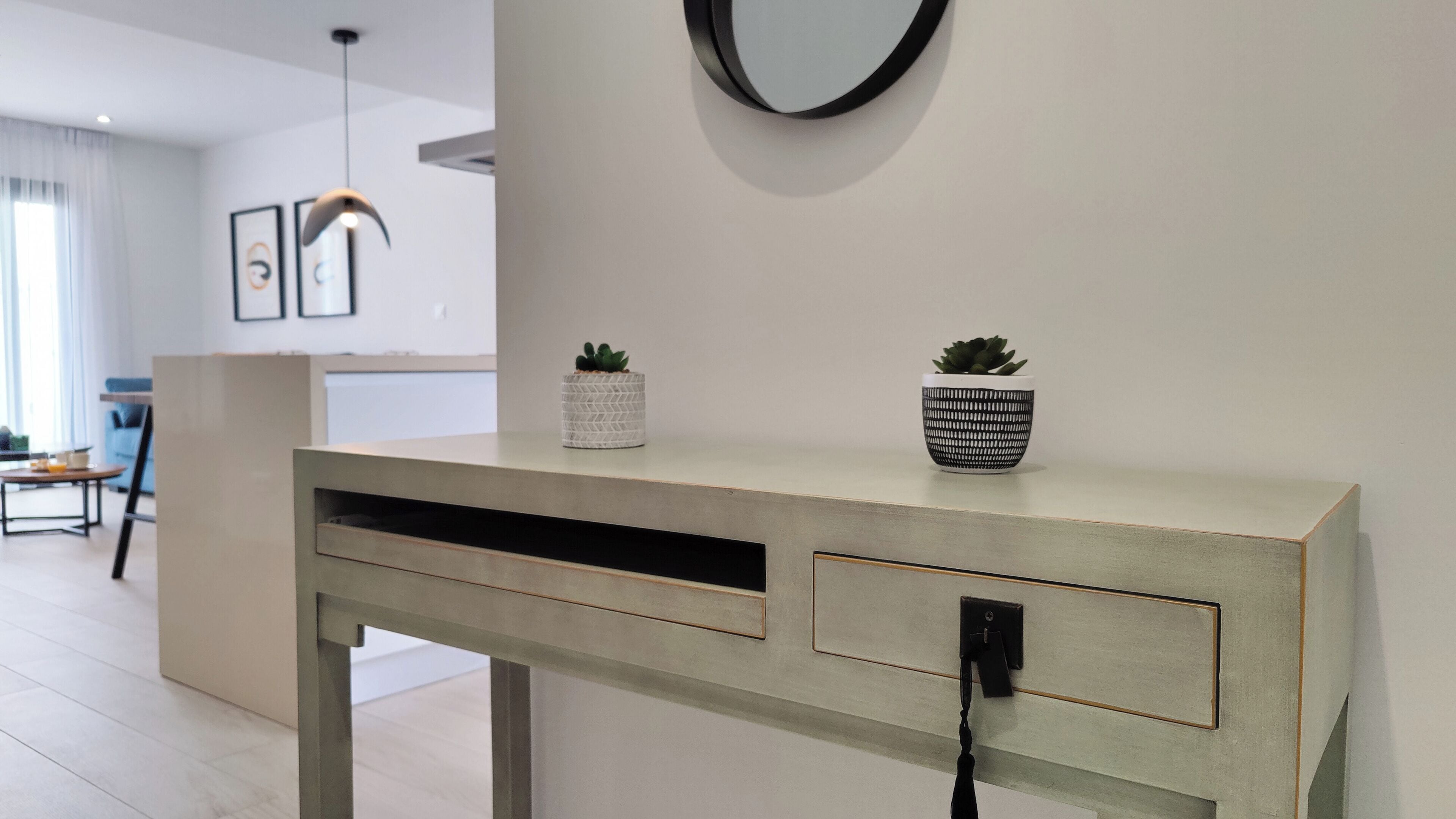 Una taula moderna amb una presa elèctrica, dues plantes en testos i un disseny minimalista.
