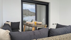 A balcony with a dining table set for two, overlooking a body of water and a mountainous landscape. - Panoramic Apartments (Finestrat)