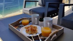 A breakfast tray with croissants and orange juice on a balcony overlooking the ocean. - Sunset Cliffs Apartments Tower 1 (Benidorm)