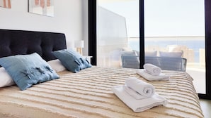 A modern hotel room with a large bed, a view of the city, and a balcony with outdoor furniture. - Sunset Cliffs Apartments Tower 1 (Benidorm)