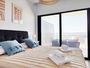 A modern hotel room with a large bed, a view of the city, and a balcony with outdoor furniture. - Sunset Cliffs Apartments Tower 1 (Benidorm)