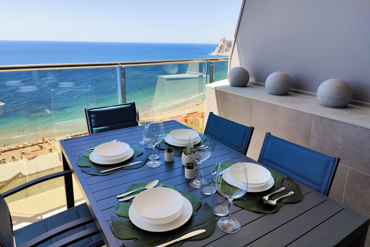 Mesa de jantar posta para dois com vista para o oceano.