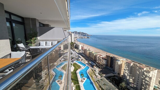 A balcony with a view of a beach, a pool, and adjacent buildings. - Sunset Cliffs Apartments Tower 2 (Benidorm)