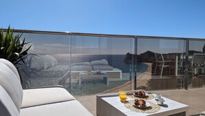 A balcony with a sofa, a table with breakfast items, and a clear view of the beach and cityscape. - Sunset Cliffs Apartments Tower 2 (Benidorm)