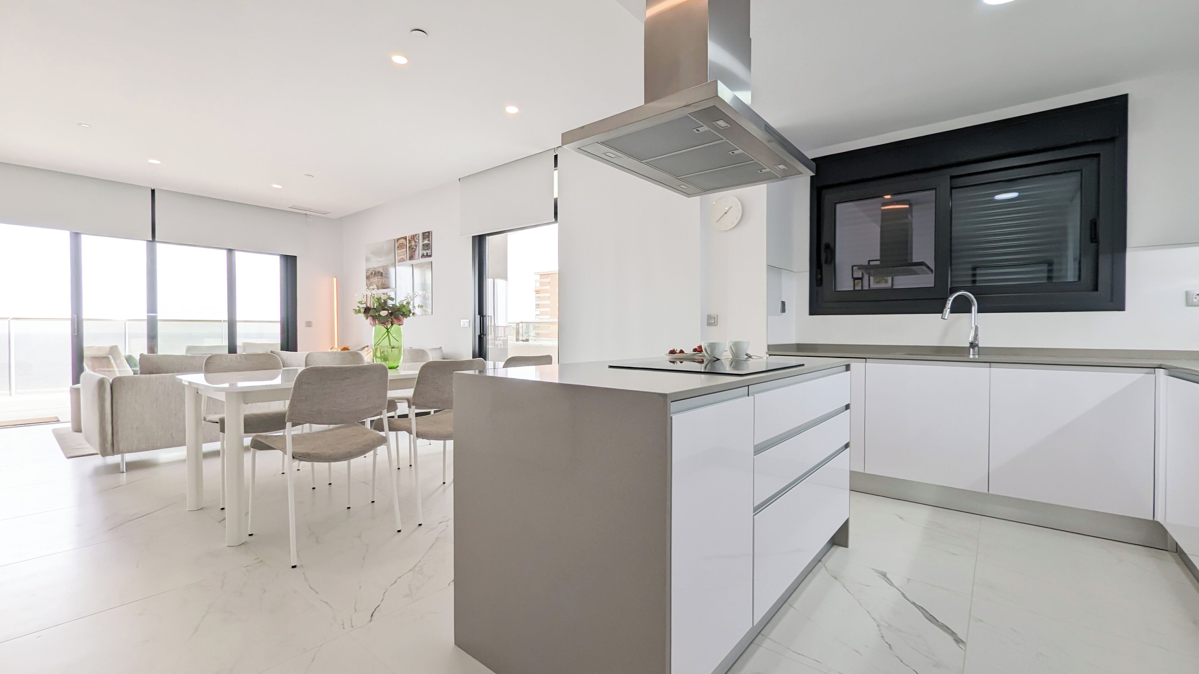 A modern kitchen with a built-in island, a dining area with a table and chairs, and a large window providing natural light.