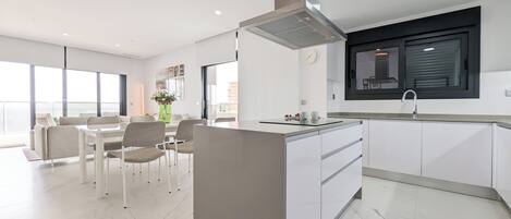 A modern kitchen with a built-in island, a dining area with a table and chairs, and a large window providing natural light.