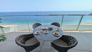 A balcony with a table set for breakfast, overlooking a beach and the sea. - Sunset Sailors Apartments (Benidorm)