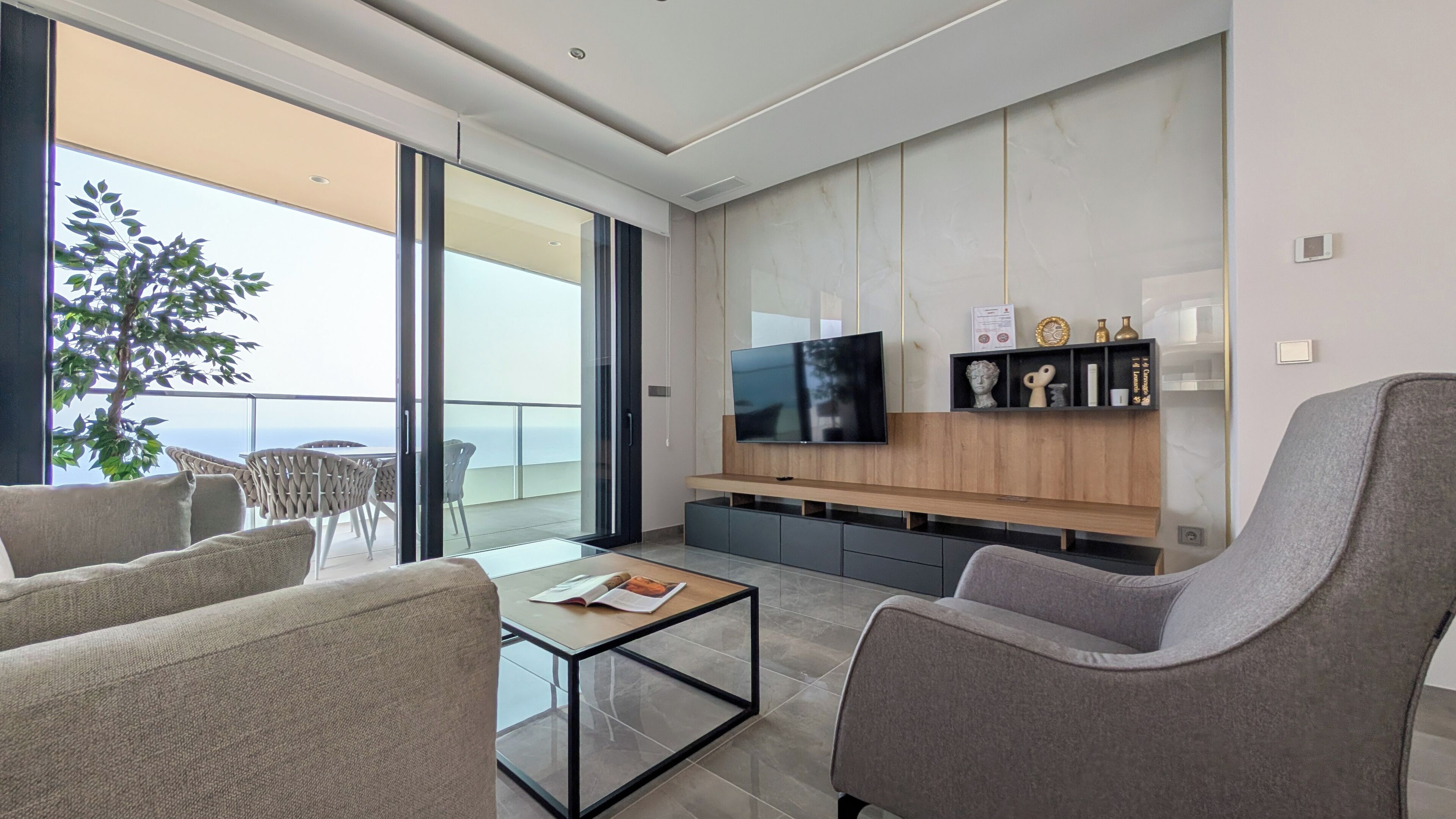 Un salon moderne doté d’un téléviseur à écran plat, de sièges confortables, d’une table basse et d’un balcon offrant une vue agréable.