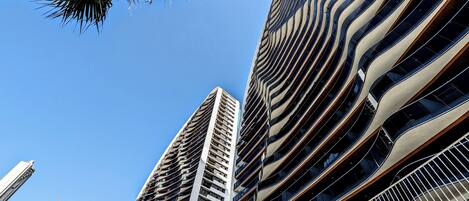 Twee hoge gebouwen met moderne architectuur, met gebogen balkons en reflecterende glazen gevels.