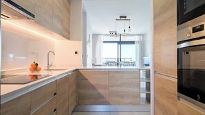 A modern kitchen with wooden cabinetry, a stainless steel sink, and a built-in oven. - Sunset Waves Apartments Tower 1 (Benidorm)