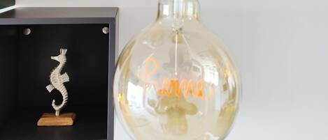 Dos lámparas de cristal esféricas con asas de cuerda, una con la palabra 'Love' y la otra con la palabra 'Home' escritas en su interior.