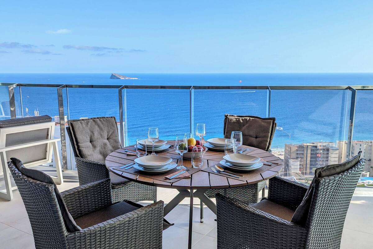 A dining table set for four with a view of the ocean.