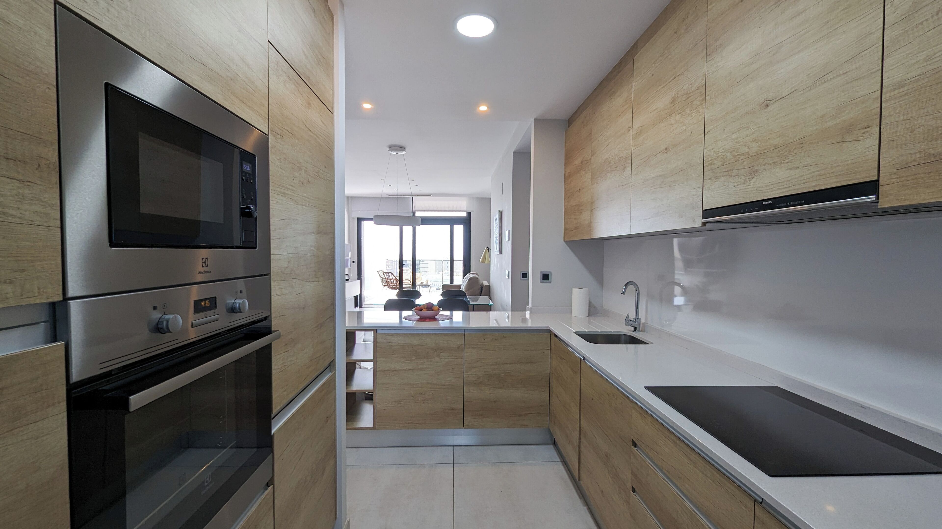 A modern kitchen with wooden cabinets, stainless steel appliances, and a central island with a sink.