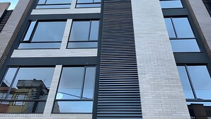 A modern building with a vertical striped facade, large windows, and a brick base. - Edificio Loft 20-51 (Bogotá)