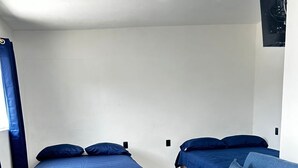 A bedroom with two beds and a sofa, white walls, and tiled flooring. - SOL Rooms (Túxpam de Rodríguez Cano)