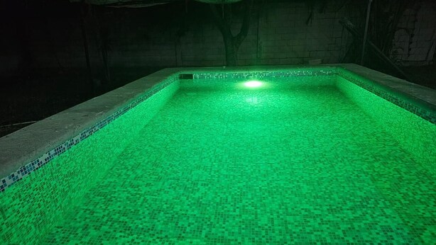A swimming pool with a green mosaic tile floor and a light source at the bottom. - SOL Rooms (Túxpam de Rodríguez Cano)