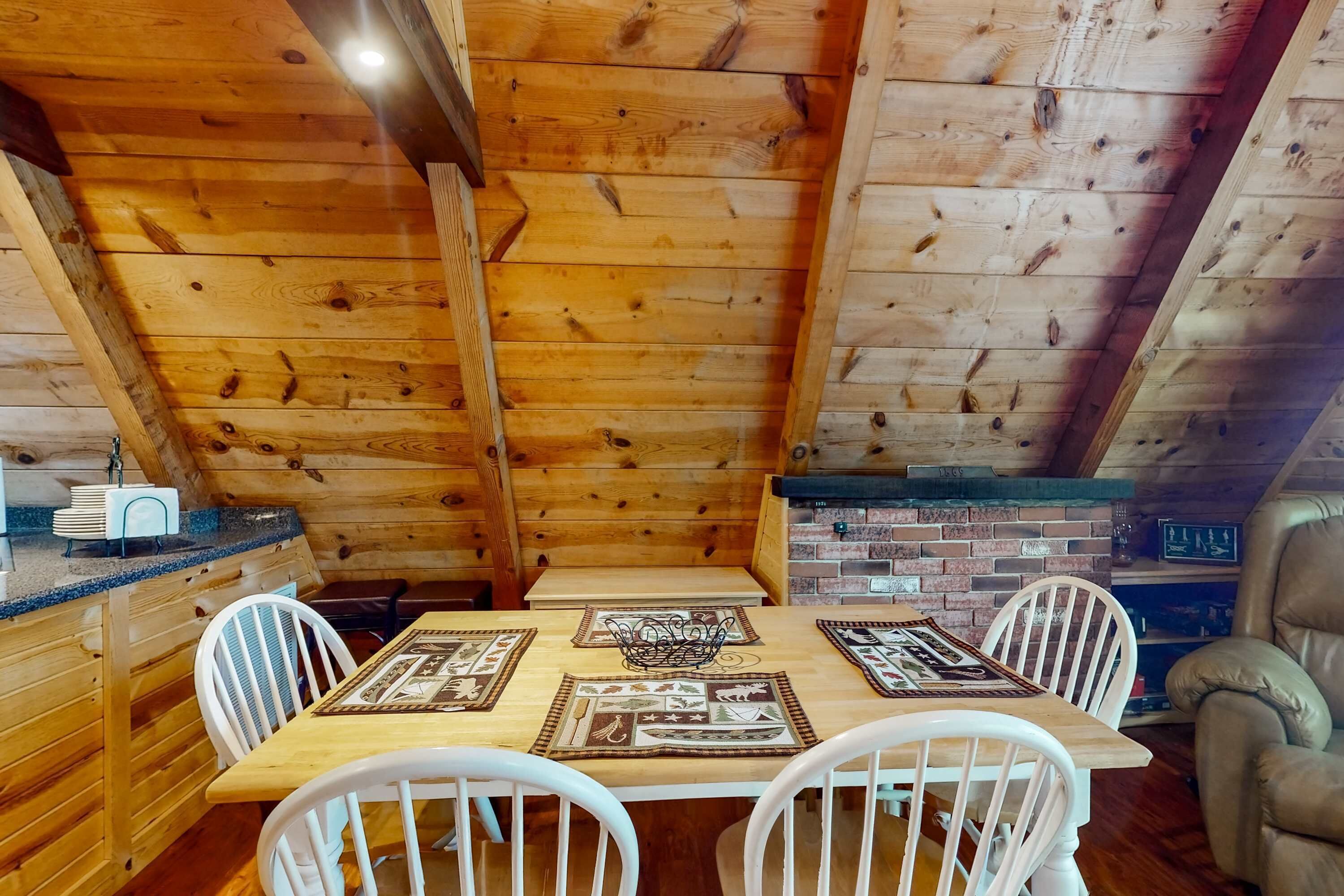 Comedor de madera con una mesa dispuesta para cuatro personas, rodeada de sillas blancas.