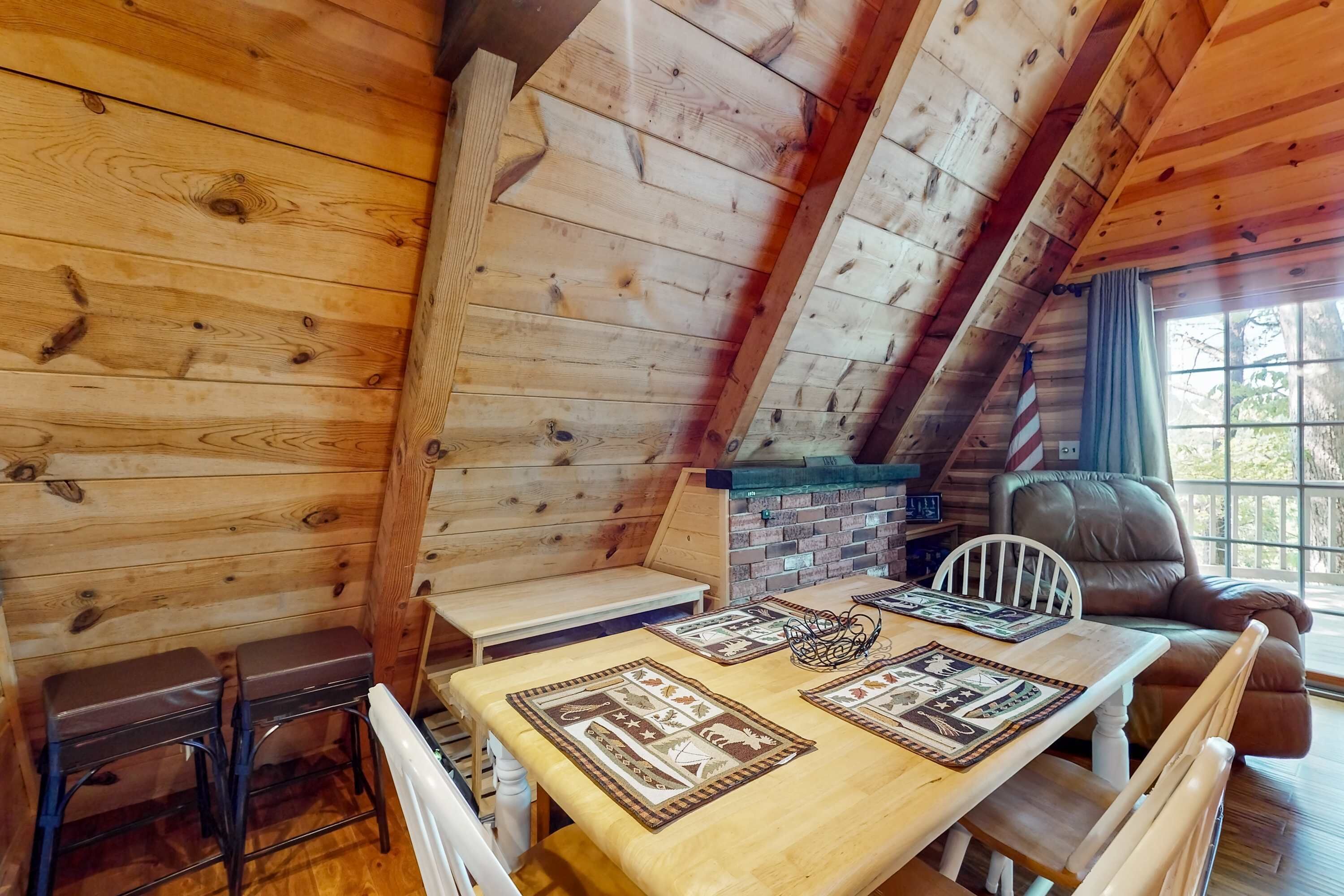 L’intérieur d’un chalet en bois chaleureux et accueillant, avec une table à manger, des chaises, un banc et un canapé en cuir.