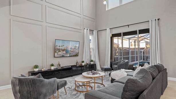 A spacious living room with a large sofa, a coffee table, and a flat-screen TV mounted on the wall. - Near Disney Villa: Private Pool & Game Room (Davenport)