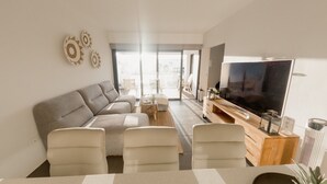 A modern living room with a grey sofa, a coffee table, and a TV on a wooden stand. - Serenidad del Sol Fuerteventura (Villaverde)