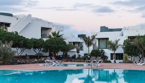 A modern resort with a swimming pool, lounge chairs, and a landscaped garden. - Serenidad del Sol Fuerteventura (Villaverde)