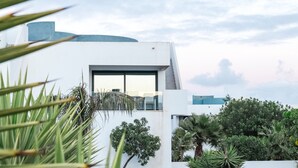 A modern building with a large window and a staircase leading to a balcony. - Serenidad del Sol Fuerteventura (Villaverde)