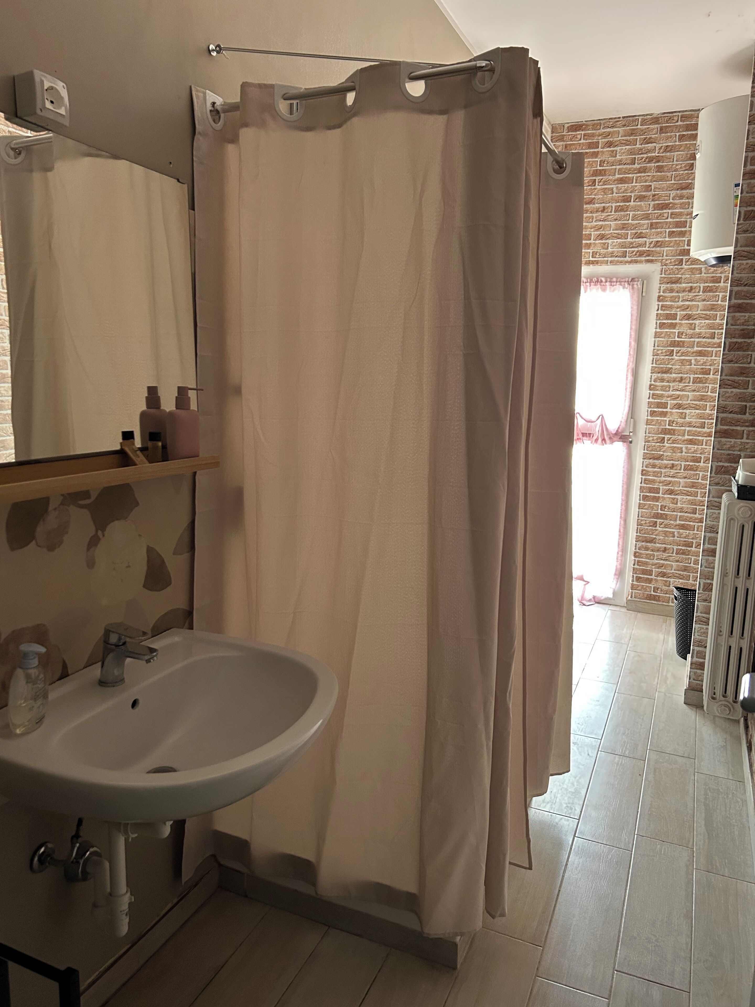 A bathroom with a shower curtain, a sink, and a mirror.