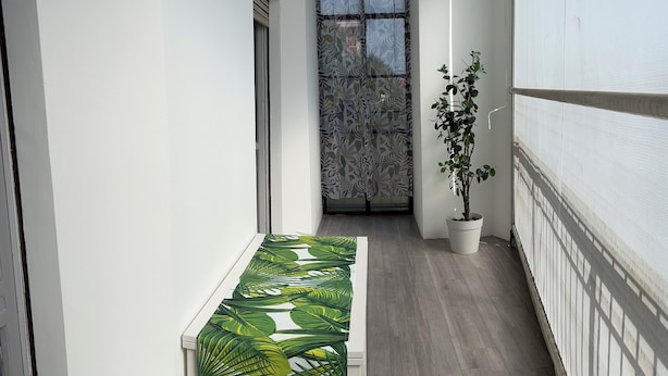 A narrow hallway with a bench, a potted plant, and a window with patterned curtains. - Relax with family or friends in this modern and unique accommodation. (Torino)