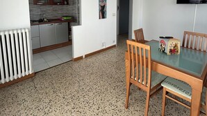 A modern kitchen with white cabinets and a built-in oven, a dining area with a glass table and wooden chairs, and a TV mounted on the wall. - Relax with family or friends in this modern and unique accommodation. (Torino)