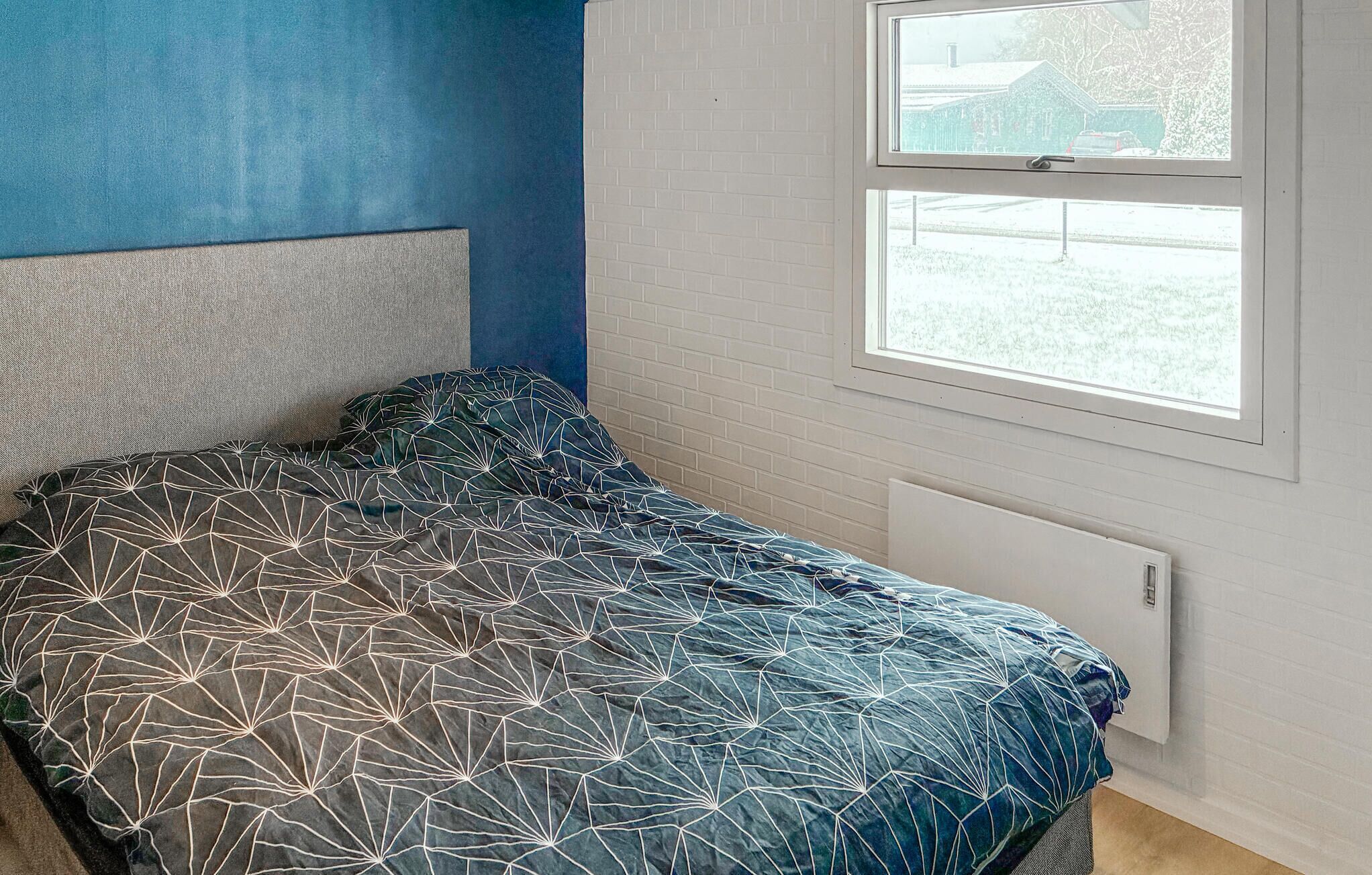 Un dormitorio con cama, ventana y radiador.