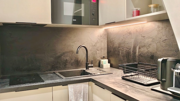 Una cucina moderna con lavello in acciaio inossidabile, forno integrato e microonde sopra il piano di lavoro.